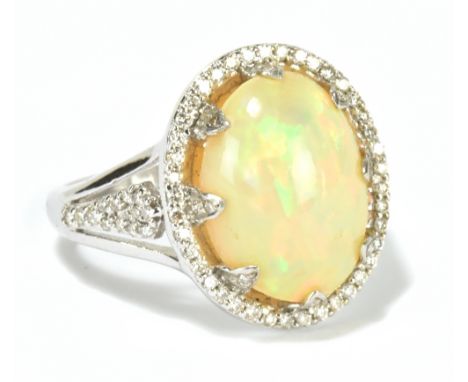 A white metal opal and diamond dress ring, the cabochon opal surrounded by a halo of melee diamonds, stamped 18K, size O, app