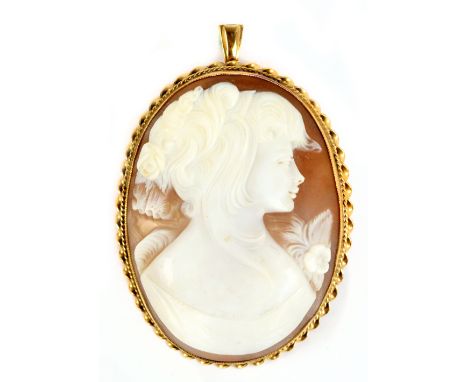 A large yellow metal framed oval cameo brooch, the plaque carved with a profile portrait of a young woman beside a floral spr