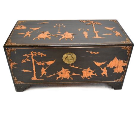 A mid-20th century Chinese camphorwood blanket box, having relief decoration depicting fighting and landscape scenes, raised 
