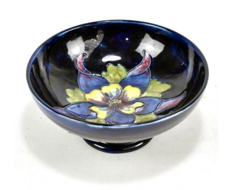 MOORCROFT; a tubeline decorated 'Clematis' pattern footed bowl on navy ground, impressed marks to base, diameter 14.3cm.Addit