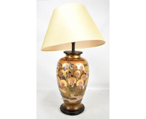 A Japanese Satsuma table lamp painted with wise men and a three claw dragon, raised on carved wooden plinth base, height excl