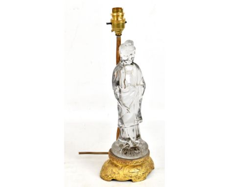 A Chinese lamp base modelled as a Buddha or Buddhist monk in imitation rock crystal on gilt metal relief decorated shaped bas