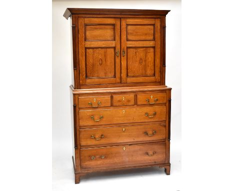 A Georgian light oak twin door cupboard on chest, the upper section having two inlaid doors above three short and three long 