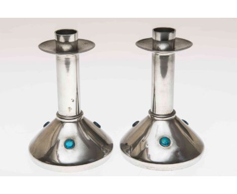 ARCHIBALD KNOX FOR LIBERTY & CO, A PAIR OF TUDRIC PEWTER AND ENAMEL CANDLESTICKS, with cylindrical stems and wide drip pans, 