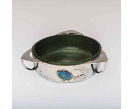 ARCHIBALD KNOX FOR LIBERTY & CO, A TUDRIC PEWTER, ENAMEL AND GREEN GLASS BOWL, circular with three lug handles, cast in low r