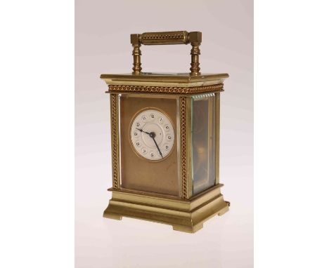 A SMALL BRASS CASED CARRIAGE CLOCK, late 19th/ early 20th Century, with circular dial, the case with bands of conjoined ringl