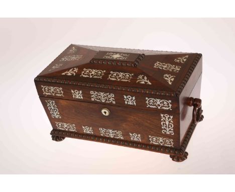 A REGENCY MOTHER-OF-PEARL INLAID ROSEWOOD TEA CADDY, of sarcophagus form with ring handles and squat reeded feet, the interio