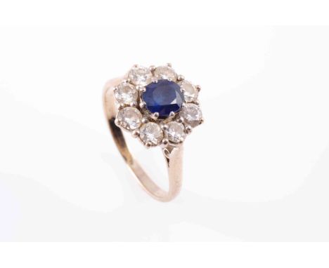 A SAPPHIRE AND DIAMOND RING, the round cut sapphire eight claw set within a surround of eight brilliant cut claw set diamonds