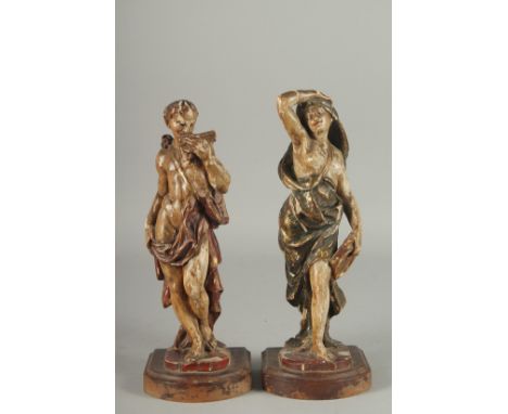 A GOOD PAIR OF 17TH - 18TH CENTURY CARVED AND POLYCHROMED WOOD FIGURES. A man playing a pan pipe and a woman carrying a cymba