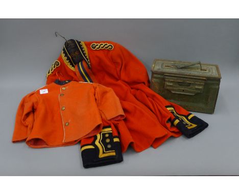 A military dress jacket, a miniature version and an ammunition box.