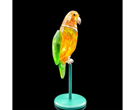 Depicts a parrot made of orange and green crystal. Black crystal and silver colored metal are used for the accents. Swarovski