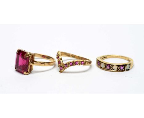 A wishbone pattern ruby ring; an opal and ruby ring; and a synthetic ruby ring, all on 9ct yellow gold shanks, 8.1g gross. 