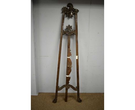 An ornate vintage stained beech easel, with carved leaf scrolling design, 64 x 220cms high.