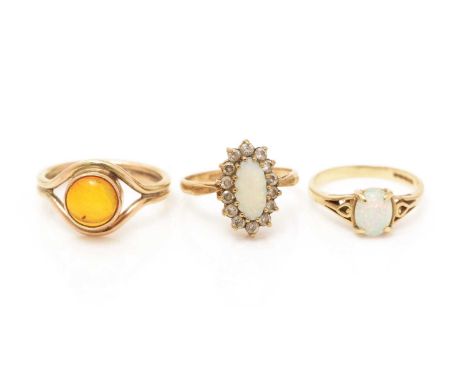 An amber cabochon ring; a white opal and white stone cluster ring; and a synthetic opal ring, all on 9ct yellow gold shanks, 