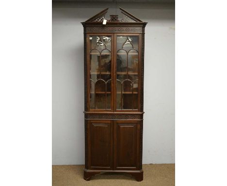 An early 20th Century mahogany full-length corner display cabinet, the pierced broken arch pediment above blind fret frieze, 