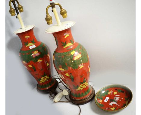 A pair of Chinese ceramic vases, decorated with a kaleidoscope of figures and foliage on a red ground, each raised upon a sta