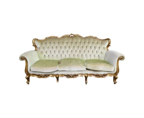 A Louis XV style button upholstered sofa - with a carved gilt frame and raised on short cabriole legs, width 200cm.