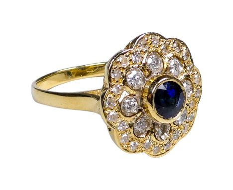 A 18ct yellow gold sapphire and diamond ring - the circular brilliant cut sapphire collet set and surrounded by diamonds, siz