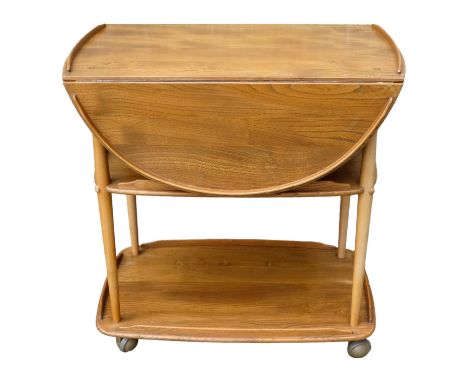 A vintage Ercol elm and beech serving trolley- the drop-leaf top with a gallery above two galleried undertiers and raised on 