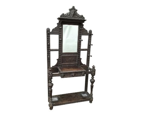 An Edwardian oak hall stand - carved with green-man head above a rectangular mirror and arrangement of pegs, the lower sectio