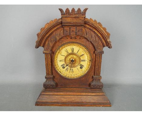 An Ansonia mantel clock having arched case with carved detailing, comes with key and pendulum, approximately 35 cm (h)