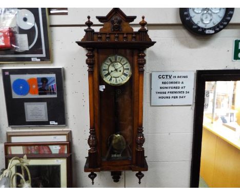 A highly carved walnut double weight Vienna wall clock with ceramic dial and pendulum   