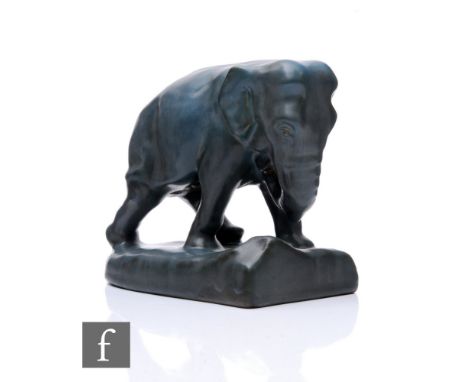 Rookwood Art Pottery - An elephant bookend, dark grey glaze, modelled striding, on naturalistic base, impressed marks to base