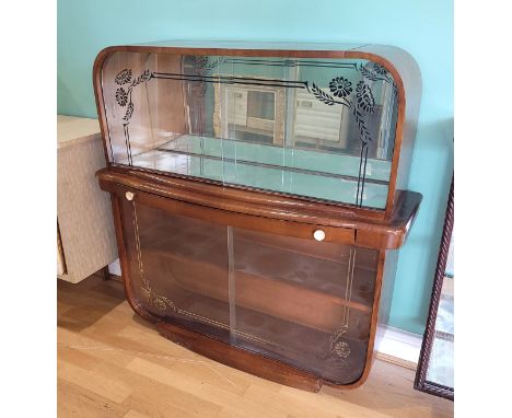 A 1920s/30s Art Deco mahogany and walnut veneered cocktail drinks cabinet, the centrally domed top over etched glass twin sli