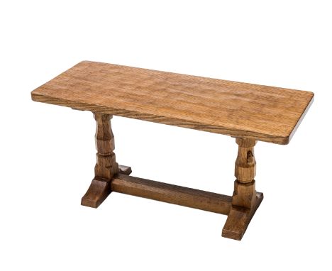 A ROBERT MOUSEMAN THOMPSON OAK COFFEE TABLE, the rectangular adzed top raised on faceted baluster legs continuing to trestles