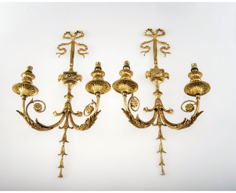 A PAIR OF GILT METAL RIBBON TIED TWIN LIGHT WALL LIGHTS, each ribbon tied over a standard flanked by rams heads, the scrollin