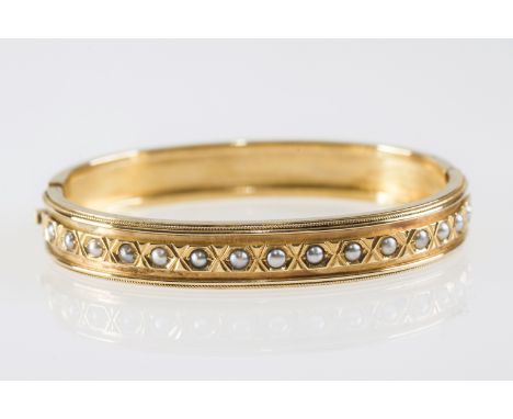 A LATE 19th CENTURY GOLD BANGLE, set to one half with seed pearls, unmarked, in a fitted velvet and silk lined leather case 