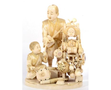 A Japanese Ivory Okimono, Meiji period, as musicians, the father playing a biwa, the son drums beside a stand of further musi