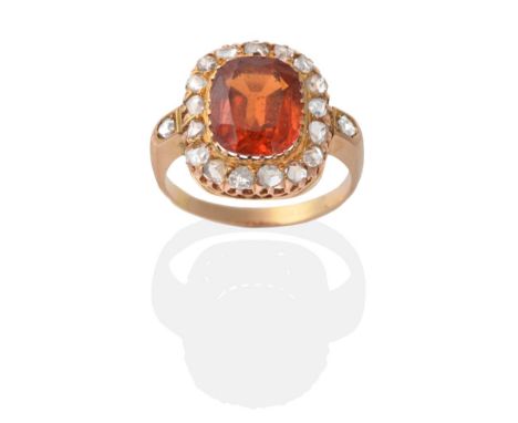 An 18 Carat Gold Hessonite Garnet and Diamond Cluster Ring, a cushion cut hessonite garnet in a collet setting, within a bord