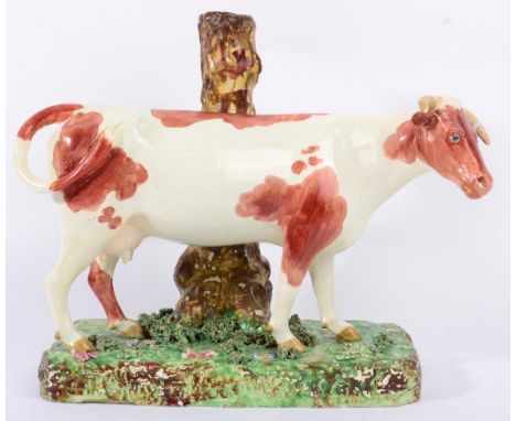 A Large Staffordshire Pottery Cow Spill Vase, early 19th century, the naturalistically modelled and painted beast standing on