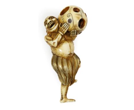 A Japanese Ivory Netsuke, Edo period, carved as a South Sea islander wearing a grass skirt holding a puzzle ball, 7.5cm high 