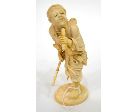 A Japanese Ivory Okimono, Meiji period, as a bearded man holding a bamboo stick and a scroll, on an oval base, signed, 18cm h