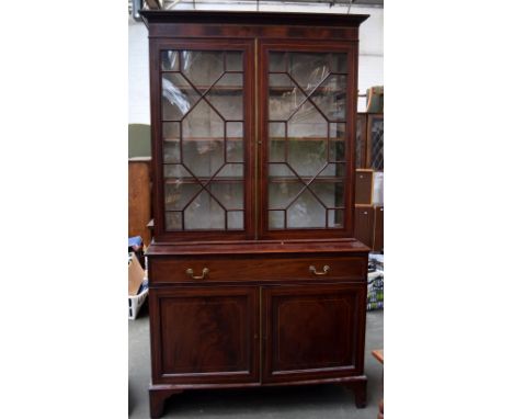 An mahogany display cabinet with astragal glazed double doors and internal shelves over long drawer, over cupboard on bracket