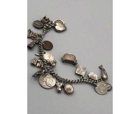 A vintage charm bracelet and charms, the bracelet is assessed as silver with a variety of mostly silver charms. Gross weight 