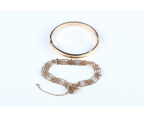 A 9ct gold oval hinged bangle, inside width 6cm, and a 9ct gold gate link bracelet on a heart shaped padlock clasp, length 18