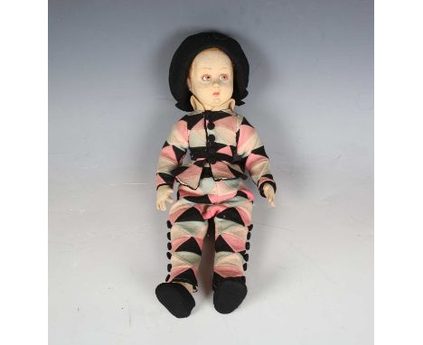 A felt doll with swivel head, red hair, painted features and jointed body, height 36cm, wearing a black hat, harlequin jacket