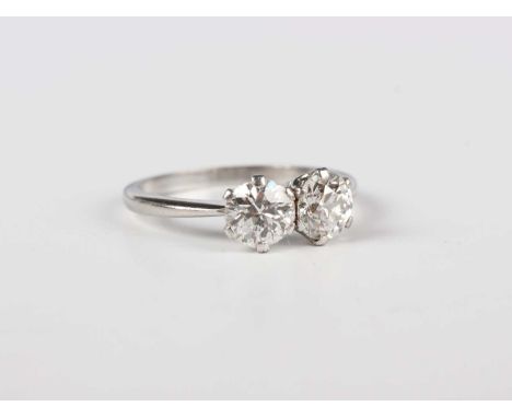 A platinum and diamond two stone ring, claw set with cushion shaped diamonds, unmarked, weight 2.9g, total diamond weight app