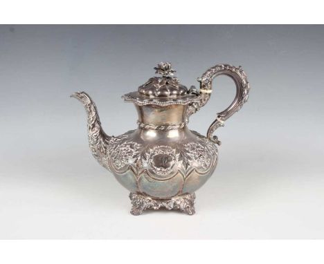 A George IV silver teapot of squat baluster form, the hinged lid with flower finial within a shaped rim above a lobed body, c