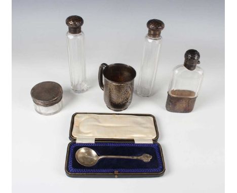 An Edwardian silver christening mug, cast in relief with an oval and scroll cartouche against a hammered ground, flanked by a