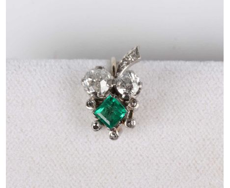A diamond and emerald earclip in a foliate design, claw set with two principal old cut cushion shaped diamonds and a square c