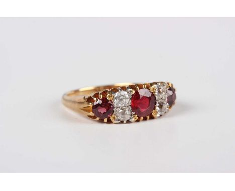 A gold, diamond and red gemstone set ring, mounted with two pairs of cushion shaped diamonds alternating with three red gemst