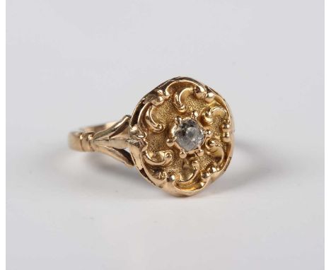 A gold and diamond single stone ring, mounted with a cushion shaped diamond within a scroll decorated shaped circular surroun