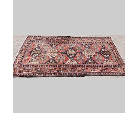 A Persian carpet, with geometric designs on a red ground, 320 x 160cm