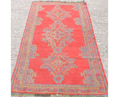 A Turkish carpet, with three central hooked medallions on a red ground, 202 x 121cm