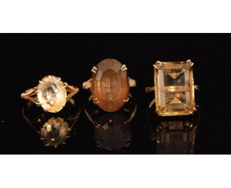 A 9ct emerald cut smokey quartz ring, another oval cut example and a citrine ring, ring sizes K, H, and L (3)