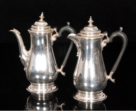 A George VI hallmarked silver cafe au lait pair, each of baluster form with domed hinged lid and bell finial, ebony scroll ha